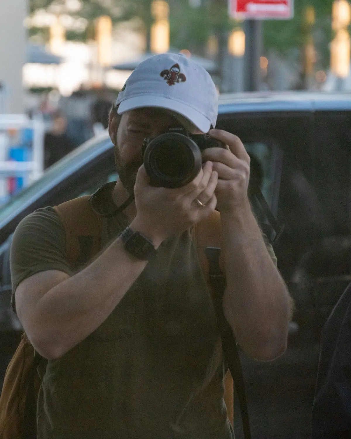 Mitchell photographing his reflection with a camera on a city street.